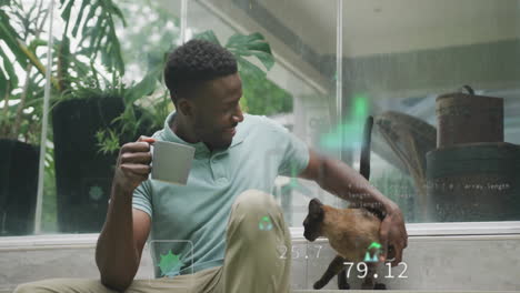 Animation-of-icon,-computer-language,-african-american-man-playing-with-dog-while-drinking-coffee