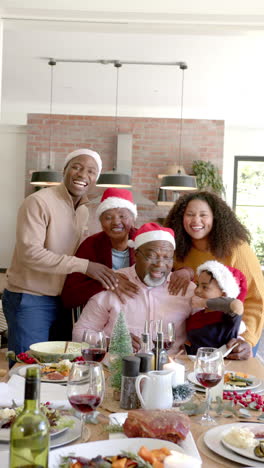 Vertical-video-portrait-of-african-american-family-at-christmas-dinner-table,-slow-motion