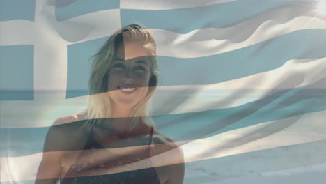 Animation-of-flag-of-greece-waving-over-smiling-caucasian-woman-standing-against-sea-at-beach