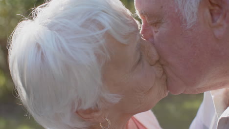 Happy-senior-caucasian-couple-kissing-in-sunny-garden,-slow-motion