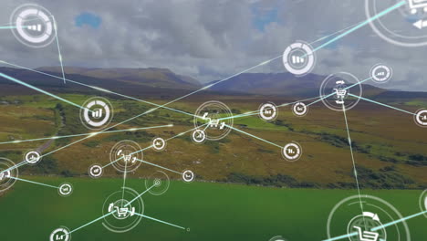 Animation-of-connected-icons-over-aerial-view-of-green-landscape-and-mountains-against-cloudy-sky