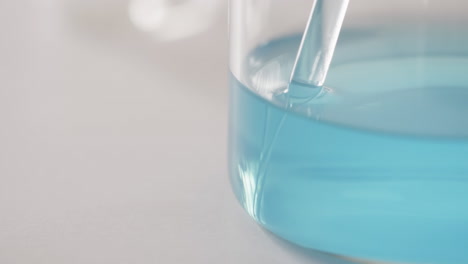 Video-Einer-Laborschale-Aus-Glas-Mit-Blauer-Flüssigkeit-Mit-Kopierraum-Auf-Weißem-Hintergrund