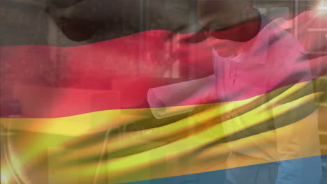 Animation-of-german-flag-over-biracial-engineer-looking-at-blueprint-of-design