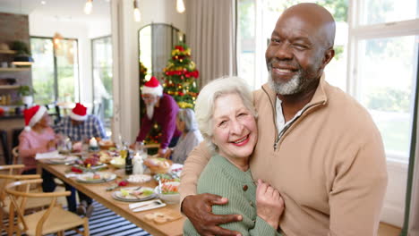 Happy-diverse-senior-couple-embracing-after-christmas-meal-with-friends,-copy-space,-slow-motion