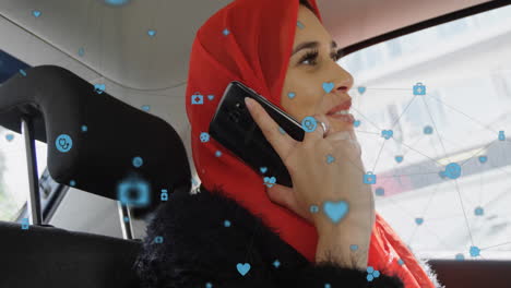 Animation-of-connected-icons,-caucasian-woman-wearing-hijab-talking-on-phone-while-sitting-in-car