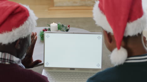 African-american-father-and-son-in-christmas-hats-having-laptop-video-call,-copy-space,-slow-motion