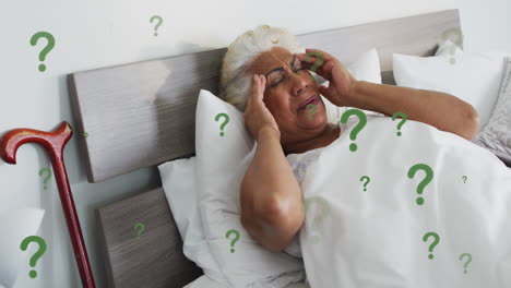 Animation-of-question-mark-symbol-over-senior-biracial-woman-suffering-from-headache
