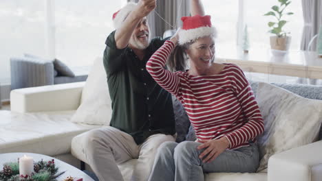 Middle-aged-caucasian-man-in-santa-hat-putting-chain-on-woman's-neck-at-christmas,-slow-motion