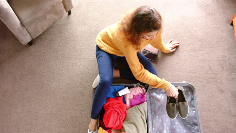 Caucasian-woman-packing-suitcase-on-floor-at-home,-copy-space,-slow-motion