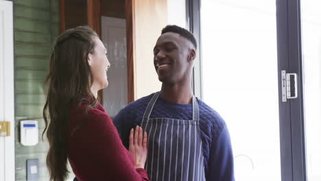 Happy-diverse-couple-standing-in-kitchen,-smiling-and-embracing,slow-motion