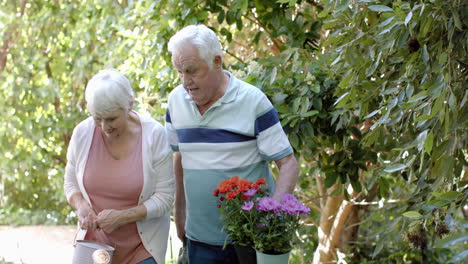 Senior-caucasian-couple-holding-flowers-in-sunny-garden,-slow-motion