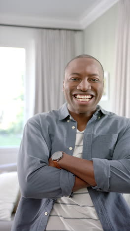 Vertikales-Videoporträt-Eines-Glücklichen-Afroamerikanischen-Mannes,-Der-Lächelnd-Im-Wohnzimmer-Steht
