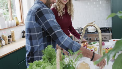 Happy-diverse-couple-preparing-dinner-in-kitchen-at-home,-in-slow-motion