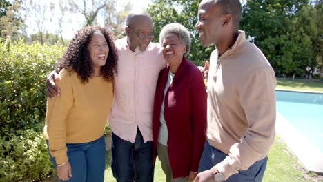 Portrait-of-happy-african-american-couple-and-senior-parents-embracing-in-sunny-garden