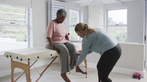 Caucasian-female-physiotherapist-checking-leg-of-senior-woman,-copy-space,-slow-motion