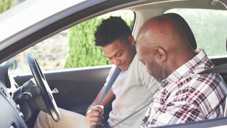 Happy-african-american-father-and-adult-son-putting-on-seatbelts-in-car-before-driving,-slow-motion