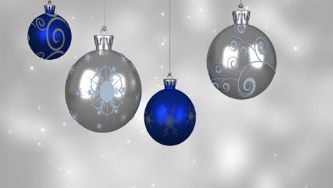 Animation-of-blue-and-silver-baubles-over-snow-falling-on-blue-background