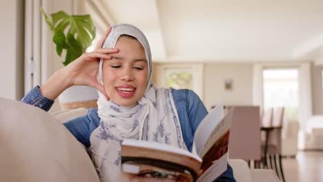 Glückliche-Biracial-Frau-Im-Hijab-Liest-Buch-Auf-Dem-Sofa-Zu-Hause-Mit-Kopierraum,-Zeitlupe