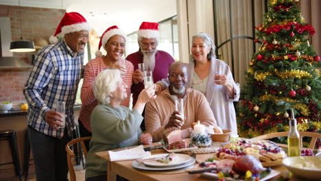 Portrait-of-happy-diverse-senior-friends-drinking-a-toast-at-christmas-dinner-table,-slow-motion