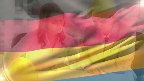 Animation-of-german-flag-waving-over-caucasian-engineers-discussing-about-design-in-office