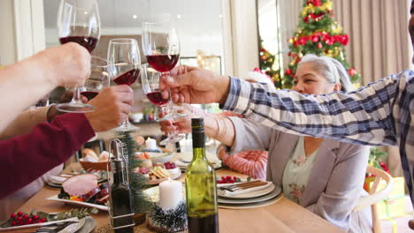 Happy-diverse-senior-friends-making-a-toast-with-wine-at-christmas-dining-table,-slow-motion