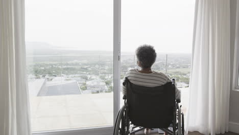 Ältere-Afroamerikanische-Frau-Im-Rollstuhl-Am-Fenster,-Kopierraum,-Zeitlupe