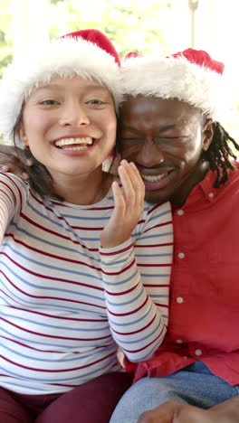 Vertical-video-of-happy-diverse-couple-making-christmas-video-call,-blowing-kisses,-slow-motion