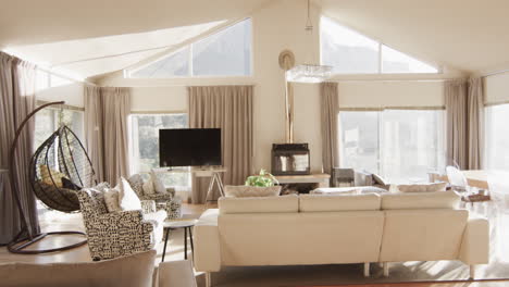 Panning-shot-of-furnished-living-room-home-interior-with-large-sunny-windows,-slow-motion