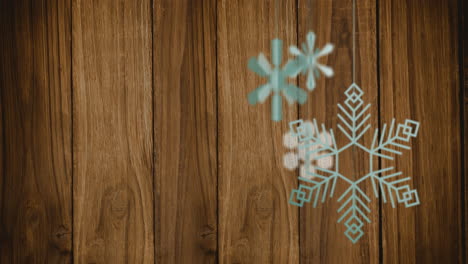 Animation-Von-Weihnachtsdekorationen-Mit-Schneeflocken-Auf-Holzhintergrund