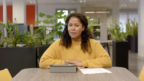 Portrait-of-casual-biracial-businesswoman-on-video-call-in-office,-slow-motion-with-copy-space