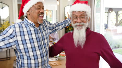 Happy-diverse-senior-male-friends-embracing-after-christmas-meal-with-friends,-slow-motion