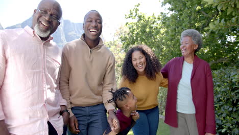 Glückliche-Afroamerikanische-Eltern-Mit-Sohn-Und-Großeltern,-Die-Zusammen-Im-Sonnigen-Garten-Spazieren-Gehen