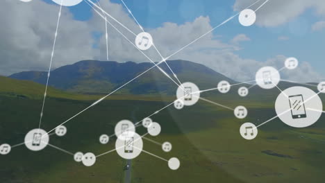 Animation-of-connected-icons-over-green-landscape-against-mountains-and-cloudy-sky
