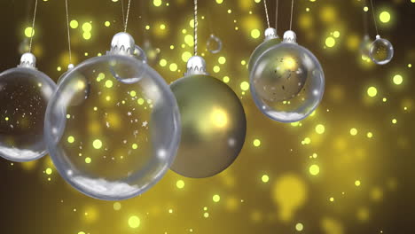 Animation-of-glass-baubles-over-snow-falling-on-yellow-background