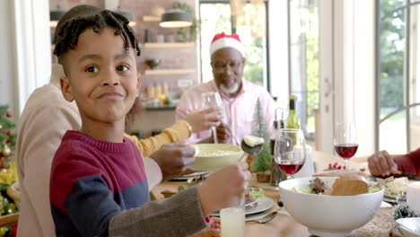 Happy-african-american-son-smiling-at-multi-generation-family-christmas-dinner-table