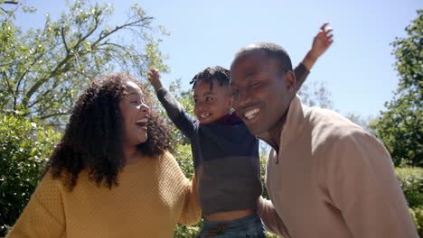 Porträt-Glücklicher-Afroamerikanischer-Eltern-Und-Sohn,-Die-Sich-Im-Sonnigen-Garten-Umarmen