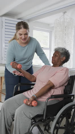Vertical-video-of-caucasian-nurse-with-senior-woman-in-wheelchair-with-copy-space,-slow-motion