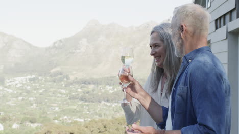 Glückliches-Kaukasisches-Paar-Mittleren-Alters,-Das-Auf-Der-Terrasse-In-Den-Bergen-Wein-Trinkt,-Zeitlupe