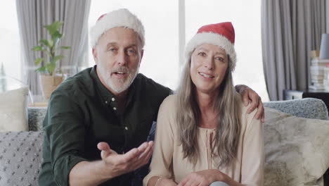 Middle-aged-caucasian-couple-in-santa-hats-on-ideo-chat-at-christmas-at-home,-slow-motion