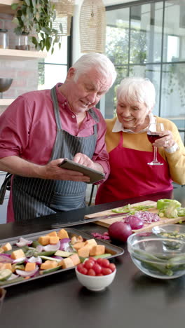 Video-Vertical-De-Una-Pareja-Caucásica-Mayor-Cocinando-La-Cena-En-La-Cocina,-Cámara-Lenta