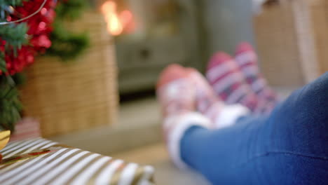 Christmas-gifts-and-feet-of-couple-in-warm-socks-by-fireplace,-copy-space,-slow-motion
