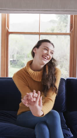 Happy-caucasian-woman-sitting-on-sofa-and-having-video-call-in-sunny-living-room,-copy-space