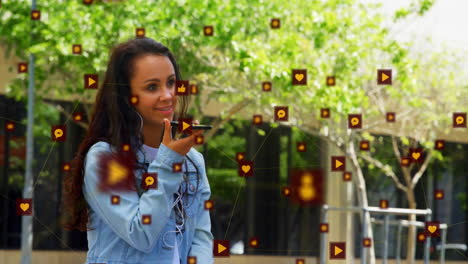 Animation-of-icons-connected-with-lines-over-biracial-woman-talking-on-speaker-of-cellphone