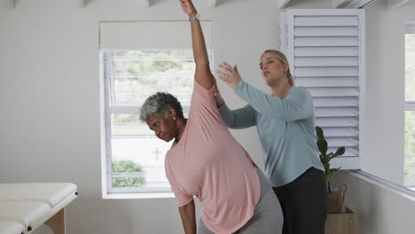 Caucasian-female-physiotherapist-with-senior-woman-exercising,-copy-space,-slow-motion