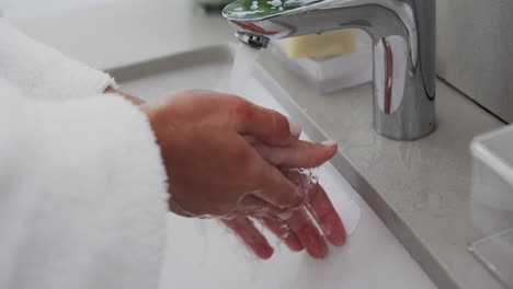 Close-up-of-biracial-woman-washing-hands-in-bathroom,-slow-motion