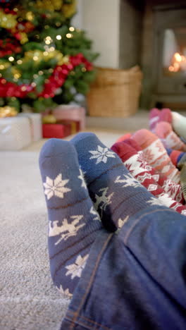 Vertical-video-of-feet-of-family-in-warm-socks-fireplace-at-christmas,-copy-space,-slow-motion