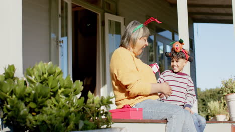 Happy-biracial-grandmother-and-grandson-giving-christmas-presents,-slow-motion,-copy-space
