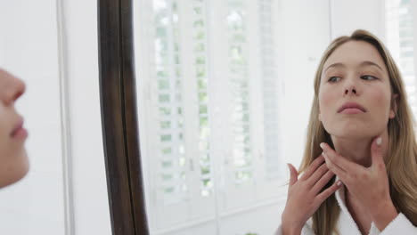 Mischlingsfrau-Berührt-Ihr-Gesicht-Und-Schaut-In-Den-Badezimmerspiegel,-Zeitlupe