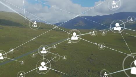 Animation-of-connected-icons-over-aerial-view-of-lush-green-mountains-against-cloudy-sky