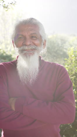 Vertical-video-portrait-of-happy-biracial-man-with-white-beard-smiling-in-sunny-nature,-slow-motion